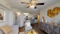 This single-floor residence offers a thoughtfully designed open-concept layout that connects the living, dining, and kitchen areas into a cohesive, functional space. The living room features wood-look flooring, a ceiling fan with light fixture, and neutral-toned walls that create a bright, welcoming atmosphere. A glass-top coffee table and mirrored accents contribute to the room's contemporary aesthetic.

The kitchen is equipped with stainless steel appliances, including a refrigerator, range, and microwave, complemented by white cabinetry, granite-style countertops, a double-basin sink, and a breakfast bar with seating. A utility closet housing the water heater is conveniently located within the kitchen area.

The primary bedroom features plush carpeting, a ceiling fan, and a window that brings in natural light. The second bedroom mirrors this comfortable layout with carpet flooring, a window with outdoor views, and a spacious reach-in closet with bifold doors.

Both bathrooms are finished with wood-look flooring, white vanity cabinetry, granite-style countertops, and shower-tub combinations. The overall design palette—neutral walls, warm wood tones, and clean white finishes—lends the residence a cohesive, modern sensibility throughout.