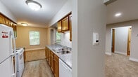 Located in Comstock Park, Michigan, this one-bedroom, one-bathroom residence offers a thoughtfully organized single-floor layout. The galley-style kitchen is a functional highlight, featuring warm honey-toned cabinetry, granite-look countertops, a double stainless steel sink, wood-look vinyl flooring, and white appliances including a range, refrigerator, and microwave. The kitchen opens toward the living area, creating a connected and practical flow between spaces. The living room is bright and spacious, finished with plush neutral carpeting and anchored by a sliding glass door that leads to a private balcony with views of lush greenery, bringing in abundant natural light. The bedroom is a comfortable, carpeted retreat with a natural light window and direct access to a dedicated closet with a rod and shelving system. Hallways connect the rooms efficiently, adding to the overall ease of navigation throughout the home. The bathroom is clean and well-equipped, featuring a full tub-shower combination, wood-tone vanity with granite-look countertop, and wood-look vinyl flooring. Neutral tones are carried throughout the entire residence, lending a cohesive and calm ambiance. This residence combines practical design with comfortable living in a convenient Comstock Park location.