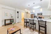 Located on Durant Avenue in Berkeley, CA, this thoughtfully designed 2-bedroom, 2-bathroom unit offers a clean, modern aesthetic throughout its single-floor layout. The open-concept kitchen and living area serves as the heart of the home, featuring a sleek white kitchen island with bar seating for three, illuminated by a trio of stylish pendant lights. The kitchen is equipped with stainless steel appliances, including a refrigerator, range, and built-in microwave, complemented by white cabinetry and a crisp countertop. The living and dining area flows seamlessly from the kitchen, with a window that invites natural light and greenery views. Light wood-toned flooring runs throughout the unit, enhancing its bright, airy feel. The primary bedroom is generously proportioned, featuring multiple windows with outdoor views, a ceiling fan, a built-in closet, and space for a desk — ideal for study or work. The second bedroom is compact yet functional, with windows on two walls providing ample natural light. Both bathrooms are finished in clean whites with full bathtub-shower combos and light wood flooring. An in-unit laundry area adds everyday convenience to this well-appointed home.