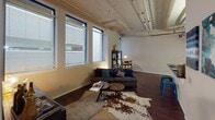 Located in Oklahoma City, the Montgomery Model showcases a compelling blend of industrial and modern design across a single-floor layout. The living area is a standout space, boasting soaring ceilings with exposed beams and piping that lend an authentic loft aesthetic. A bank of large windows floods the room with natural light, highlighting rich, dark hardwood flooring that runs throughout the main living spaces. The kitchen features deep-toned cabinetry with raised panel detailing, dark granite countertops, and stainless steel appliances, creating a refined yet functional workspace. The bedroom continues the industrial-chic theme with elevated ceilings, a ceiling fan, exposed ceiling infrastructure, and direct access to a well-appointed en-suite bathroom. The bathroom is finished with matching dark granite countertops, rich wood cabinetry, a full vanity mirror, and a tiled tub-shower combination. The overall ambiance of the Montgomery Model is one of urban sophistication — open, airy, and thoughtfully designed with a cohesive palette of warm neutrals and bold contrasting finishes that reflect the character of its Oklahoma City location.