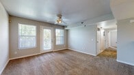 Located at 2001 W 6th St in Lawrence, Kansas, this single-floor, 3-bedroom, 2-bathroom residence offers a practical and well-organized layout. The living room serves as the heart of the home, featuring warm neutral-toned carpet, a ceiling fan with light fixture, and multiple windows alongside a glass-panel exterior door that invites natural light and outdoor views. The space connects openly to the kitchen, which is accessible via a defined archway with a convenient pass-through counter. The galley-style kitchen is well-equipped with warm oak cabinetry, ample counter space, tile flooring, and white appliances including a range, microwave, dishwasher, and refrigerator. Three carpeted bedrooms provide comfortable retreats, each featuring neutral walls, blinds-fitted windows with natural light, and closet access. The primary bedroom offers a generous footprint with an adjacent bathroom featuring warm-toned tile flooring, a long vanity with storage cabinetry, and a mirror. The second bathroom includes tile flooring and a tub/shower combination with sliding glass doors. Throughout the home, consistent neutral paint tones, white trim, and carpeted living areas create a clean, cohesive aesthetic well-suited for residents in Lawrence, KS.