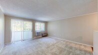 Located at 100 Clearwater Dr in Falmouth, Maine, this two-bedroom, one-bathroom single-floor residence offers a practical and well-appointed layout. The living room is bright and spacious, featuring neutral-toned carpet, a textured ceiling, crown molding, and a sliding glass door with vertical blinds that invites natural light and outdoor views. A wall-mounted air conditioning unit and baseboard heater provide year-round climate control.

The kitchen has been thoughtfully updated with white shaker-style cabinetry, dark countertops, a mosaic tile backsplash, and wood-look flooring. It is fully equipped with stainless steel appliances, including a gas range, microwave, dishwasher, and refrigerator.

Both bedrooms are carpeted and filled with natural light from large windows fitted with vertical blinds. The spacious primary bedroom includes baseboard heating and ample room for furnishings. Closets are generously distributed throughout, with three total providing excellent storage capacity.

The bathroom features a white vanity with a framed mirror, a tiled tub-shower combination, and wood-look flooring. A connecting hallway ties all rooms together efficiently. The overall aesthetic is clean and neutral, offering a move-in ready environment in a convenient Falmouth location.