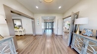 The Meadowridge Lane Leasing Center in Montgomery, Alabama, is a thoughtfully designed single-floor facility that serves as a welcoming hub for prospective residents. The space opens into a bright, well-lit corridor featuring warm wood-look flooring, recessed lighting, and glass-paneled entry doors that draw natural light deep into the hallway, creating an inviting first impression.

The lounge area is a standout feature, boasting floor-to-ceiling windows that frame sweeping views of the outdoor pool and patio, flooding the room with abundant natural light. Elegantly furnished with plush accent chairs and a glass-top coffee table, this space exudes a calm, sophisticated ambiance.

Two distinct dining areas offer flexible gathering spaces. One features a tray ceiling, large windows with neutral drapery, and a substantial dark wood dining table with cognac leather chairs. The other presents a bright, airy setting with vaulted ceilings, a round marble-top table, and direct access to the pool area via French doors.

A practical workspace includes an island with bar seating, dark granite countertops, and ample white cabinetry — ideal for leasing or administrative functions.

The spacious fitness center is equipped with strength machines, free weights, resistance equipment, and stability balls, all set on durable rubber flooring with bright, even overhead lighting. Together, these areas create a polished, functional, and welcoming leasing environment.