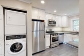 Located at 14 Bliss Ave in Tenafly, NJ, this well-appointed one-bedroom, one-bathroom unit offers a thoughtfully designed layout across a single floor. Rich hardwood flooring and crisp crown molding flow throughout the living and bedroom spaces, lending a polished, classic character to the interior. Recessed lighting brightens each room, complemented by large windows that invite generous natural light and outdoor views of surrounding greenery.

The spacious living room provides a comfortable gathering area, while the kitchen is outfitted with white shaker cabinetry, dark countertops, stainless steel appliances — including a refrigerator, gas range, and microwave — and gray tile flooring. A dedicated pantry offers additional storage. In-unit laundry is conveniently housed in a closeted stacked washer and dryer unit adjacent to the kitchen.

The bedroom is a well-sized retreat featuring hardwood floors, a ceiling fan, recessed lighting, and a bright window. Two closets provide ample storage throughout the unit. The bathroom features a soaking tub with elegant marble-style tile surround and chrome fixtures. Crown molding and neutral warm-toned walls tie the entire space together for a clean, move-in-ready aesthetic.