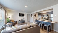 Located at 301 Campusview Dr in Columbia, Missouri, this single-floor unit offers a well-designed, modern living experience with a cohesive contemporary aesthetic throughout. The open-concept living and dining area is bright and welcoming, featuring large windows that allow generous natural light to fill the space, light wood-style flooring, and a textured ceiling. A wall-mounted TV and comfortable seating make the living area ideal for relaxing or entertaining. The kitchen flows seamlessly from the living space and is outfitted with dark wood-tone cabinetry, stainless steel appliances including a refrigerator, electric range, microwave, and dishwasher, as well as a breakfast bar with industrial-style counter seating. In-unit laundry is also accessible from the kitchen area. The unit includes multiple bedrooms, each with light flooring, ample closet space, and windows providing natural light. The bedrooms offer versatile layouts suitable for both sleeping and study or workspace arrangements. The bathrooms feature modern dark wood-tone vanities with white countertops, large mirrors, well-lit fixtures, and shower-tub combinations, reflecting the same clean, updated style found throughout the rest of the unit. Overall, the space presents a functional and stylish environment well-suited for everyday living.