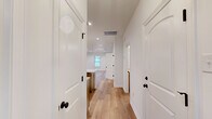 This single-story home offers a thoughtfully designed layout that maximizes functionality and comfort. Wide-plank hardwood flooring runs consistently throughout, unifying the space with a warm, contemporary aesthetic. The entrance leads into a bright hallway, providing access to the main living areas and bedrooms via classic paneled white doors with sleek matte black hardware.

The open-concept kitchen and living room serves as the heart of the home. The kitchen features warm-toned wood cabinetry, granite countertops, a large center island with a built-in sink and matte black faucet, stainless steel appliances, and pendant lighting overhead. The living area benefits from recessed lighting and access to the outdoors through a glass-paned door and a window that invites natural light.

The primary bedroom is generously sized, offering a ceiling fan with lighting and a spacious walk-in closet outfitted with built-in shelving and hanging rods. The en-suite bathroom includes wood cabinetry with granite countertops and a full tub-shower combo. The second bedroom is bright and airy, with a ceiling fan and a window overlooking the outdoors.

Both bathrooms are finished consistently with warm cabinetry, granite counters, and matte black fixtures. A dedicated laundry room and three closets provide ample storage throughout the home.