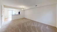 This two-story residence offers a practical and well-organized layout across two floors. The main level features a carpeted living area with neutral walls, a front entry door, and a staircase leading to the upper level. A pass-through opening connects the living space to the kitchen, enhancing the sense of openness between the two areas. The kitchen is equipped with rich, dark espresso-toned cabinetry, light granite-style countertops, hardwood flooring, and black appliances including a refrigerator, range, microwave, and dishwasher. A half bathroom on the main level includes a dark wood vanity with a white countertop, framed mirror, and chrome fixtures. Upstairs, two carpeted bedrooms offer comfortable living spaces with neutral walls and ample natural light. Each bedroom includes closet access, with at least one featuring a walk-in style closet. The full bathroom upstairs is finished with a dark wood vanity, white countertop, and a framed mirror. Throughout the home, the light-toned carpet, white walls, and clean finishes create a bright, functional living environment.