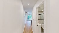 Located at 5205-5215 1re Ave in Montréal, this thoughtfully designed unit makes efficient use of its compact footprint across a single floor. The open-concept living and kitchen area is bright and airy, anchored by light wood-tone flooring and crisp white walls that maximize the sense of space. Recessed lighting throughout provides consistent illumination, while a sliding glass door opens onto a private balcony overlooking lush greenery, filling the interior with natural light.

The kitchen is well-appointed with a peninsula island featuring a white quartz countertop and a sleek matte black faucet with an undermount stainless steel sink. White shaker-style cabinetry with black hardware lines the walls, complemented by a stainless steel refrigerator and range. A marble-look tile backsplash adds a refined touch. A wall-mounted mini-split unit provides efficient climate control for the living area.

The bathroom is a standout feature, finished entirely in large-format marble-effect tiles from floor to ceiling. It includes a frameless glass sliding shower enclosure with matte black hardware, a wall-mounted vanity mirror with matching black trim, and a clean, modern toilet. The overall design is cohesive and contemporary, delivering a polished, move-in-ready space ideal for those seeking functional urban living in Montréal.