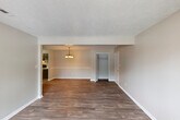 Located at 2130 Westmead Dr SW in Decatur, Alabama, this single-floor home offers a well-organized layout with consistent wood-look flooring and neutral warm-toned walls throughout. The living area is open and generously sized, flowing naturally into a dedicated dining space outfitted with a classic chandelier and a decorative chair rail that adds a refined architectural detail to the room. A built-in closet with rod and shelf storage is conveniently accessible from the main living area. The dining room opens directly into the galley-style kitchen, which features dark cabinetry, light countertops, a double-basin sink, and black appliances including an electric range and refrigerator. A separate pantry with open shelving provides additional storage. The kitchen connects back through to the rest of the home, creating a practical and efficient flow. The bedrooms are comfortably sized with the same wood-look flooring, neutral walls, and ample natural light provided by windows with blinds. One bedroom includes a private en-suite bathroom. Textured ceilings are present throughout the home. An exterior door with a multi-pane window leads outside, allowing additional natural light into the space. Overall, the home presents a clean, functional, and move-in ready environment.