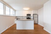 Located at 139 Brock St E in Oshawa, Ontario, this two-storey home offers three bedrooms and one bathroom across a well-distributed layout. The main floor opens to a bright living area featuring warm hardwood flooring and a staircase with white-painted railings. The kitchen is well-appointed with white shaker-style cabinetry, stainless steel appliances including a fridge, range, and microwave, a double sink, and a central island with neutral countertops — all tied together with warm wood flooring and ample natural light from a wide window. A dedicated laundry room on the main floor includes a full washer and dryer alongside a utility sink and water heater, adding functional convenience. The staircase leads to the upper floor, where three bedrooms are located, including a generously sized primary bedroom. Two of the bedrooms feature classic parquet wood flooring that adds character, while the primary bedroom showcases light plank hardwood with multi-pane windows providing natural light and treetop views. The shared full bathroom is clean and functional, complete with a tiled tub-shower combination, toilet, and vanity. Throughout the home, neutral grey-white walls and textured ceilings create a consistent, understated aesthetic well-suited for comfortable everyday living.