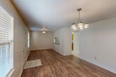 Located at 4802 Pontchartrain Dr in Slidell, Louisiana, this single-story, 2-bedroom, 1-bathroom home offers a practical and efficient layout. The combined living and dining area forms the heart of the home, featuring warm wood-look flooring, a textured ceiling, and an elegant chandelier that anchors the dining space. Natural light filters in through blinded windows, and a front entry door with a sidelight window provides a welcoming arrival. A distinctive pass-through window connects the living/dining area directly to the kitchen, enhancing the open feel of the space. The galley-style kitchen is well-appointed with warm honey-toned cabinetry, laminate countertops, a stainless steel refrigerator, an electric range, a built-in dishwasher, and a double-basin sink — all set on light tile flooring. A pantry adds extra storage convenience. The two bedrooms continue the wood-look flooring and feature closets, with the primary bedroom offering ample space. The bathroom is thoughtfully combined with the laundry area, housing a tub/shower combo, a vanity with cabinetry, tile flooring, and washer/dryer units with open shelving above. A hallway with additional closets connects the private areas of the home, completing this well-organized and functional layout.