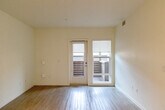 Located at 868 S Fifth St in San Jose, CA, this well-designed one-bedroom, one-bathroom unit offers a thoughtfully laid-out single-floor plan. The open-concept living and kitchen area is finished with light wood-style flooring that creates a bright, cohesive aesthetic throughout. The kitchen is a standout feature, equipped with stainless steel appliances including a refrigerator, range with microwave, and dishwasher. Cabinetry combines crisp white upper cabinets with warm natural wood lower cabinets, complemented by clean white countertops and a stainless steel sink. The living area flows seamlessly toward a set of glass doors that open to a private balcony, allowing natural light to fill the space. The bedroom is carpeted for comfort, featuring neutral walls and a large window that brings in additional natural light and street views. A dedicated closet provides convenient storage. The bathroom is finished with wood-toned cabinetry, a white countertop vanity, a large mirror, and wood-look tile flooring, with accessibility grab bars thoughtfully included. A hallway connects the rooms, contributing to the unit's efficient and functional layout. The overall design is modern, clean, and understated, making it a practical and comfortable space.
