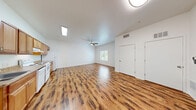 Located at 511 College Dr in Henderson, NV, this one-bedroom, one-bathroom unit offers a well-organized single-level layout that makes efficient use of its space. The open living area is anchored by rich, wood-style laminate flooring that flows throughout the main living spaces, complemented by bright white walls and a ceiling fan with light fixture that enhances both comfort and illumination. A window allows natural light to fill the room, creating an airy, welcoming atmosphere.

The kitchen runs along one wall in a galley-style configuration, featuring warm honey-toned wood cabinetry, granite-look countertops, a double sink, and white appliances including a refrigerator, electric range, and dishwasher. A skylight overhead adds additional brightness to the cooking area.

The bedroom is finished with plush, neutral-toned carpet for added comfort and includes a set of sliding bypass closet doors for convenient storage. A window provides natural light and outdoor views.

The bathroom is thoughtfully designed with accessibility in mind, equipped with grab bars throughout, a walk-in shower with built-in shelving, wood-style flooring, a wooden vanity with granite-look countertop, and a large mirror. Clean white walls tie the space together with a crisp, functional aesthetic throughout.