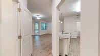 Located at 138 Inspiration Ave in Bluffton, SC, this one-bedroom, one-bathroom residence offers a thoughtfully designed single-floor layout with modern finishes throughout. The open-concept living area is bathed in natural light, thanks to multiple large windows and a glass-panel door leading to an outdoor balcony, offering pleasant views of surrounding greenery. Light-toned wood-style flooring runs throughout the main living spaces, creating a clean and cohesive aesthetic.

The kitchen is a standout feature, equipped with stainless steel appliances including a refrigerator, range, and built-in microwave. White shaker-style cabinetry provides ample storage, while granite countertops extend across the workspace and a peninsula with an undermount sink — ideal for casual dining or meal prep. Pendant lighting adds a polished finishing touch.

The bedroom is carpeted for comfort and features a window with views of lush landscaping, allowing for plenty of natural light. The full bathroom continues the granite countertop theme with a white vanity, undermount sink, and a tub-shower combination. Additional highlights include a dedicated laundry area with a full-size washer and dryer, as well as a closet for extra storage. The overall ambiance is clean, bright, and move-in ready.