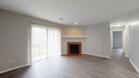 Located at 3775 Westmont Dr. in Cincinnati, Ohio, this single-floor residence offers a well-organized layout with a seamless flow between living, dining, and kitchen spaces. The living room is a standout area, featuring a classic brick-tile surround fireplace with a white mantel, wood-look vinyl plank flooring, and sliding glass doors with vertical blinds that open to a private balcony, allowing an abundance of natural light into the space. An exposed white-painted brick accent wall adds a distinctive architectural character to the room.

The kitchen is designed for functionality, showcasing dark cabinetry contrasted against light granite-style countertops, a double sink, a built-in breakfast bar peninsula, and black appliances including a full-size refrigerator. The wood-look flooring continues throughout, creating a cohesive aesthetic across the home.

The bedrooms are comfortably sized, each featuring natural light from windows, neutral gray walls, and generous closet space — including a walk-in closet in the primary bedroom. The bathroom is finished with classic white tile surrounding the tub-shower combo, a white vanity, and wood-look flooring. Throughout the home, clean lines, neutral tones, and consistent finishes create a cohesive and move-in-ready environment.