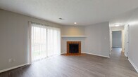 Located at 3775 Westmont Dr. in Cincinnati, Ohio, this single-floor residence offers a well-organized layout with a seamless flow between living, dining, and kitchen spaces. The living room is a standout area, featuring a classic brick-tile surround fireplace with a white mantel, wood-look vinyl plank flooring, and sliding glass doors with vertical blinds that open to a private balcony, allowing an abundance of natural light into the space. An exposed white-painted brick accent wall adds a distinctive architectural character to the room.

The kitchen is designed for functionality, showcasing dark cabinetry contrasted against light granite-style countertops, a double sink, a built-in breakfast bar peninsula, and black appliances including a full-size refrigerator. The wood-look flooring continues throughout, creating a cohesive aesthetic across the home.

The bedrooms are comfortably sized, each featuring natural light from windows, neutral gray walls, and generous closet space — including a walk-in closet in the primary bedroom. The bathroom is finished with classic white tile surrounding the tub-shower combo, a white vanity, and wood-look flooring. Throughout the home, clean lines, neutral tones, and consistent finishes create a cohesive and move-in-ready environment.