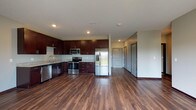 This single-floor residence offers a thoughtfully designed open layout that seamlessly connects the kitchen, dining, and living areas. The kitchen is a standout feature, showcasing rich dark espresso cabinetry that extends to the ceiling, light granite countertops, and a full suite of stainless steel appliances including a refrigerator with ice and water dispenser, electric range, built-in microwave, and dishwasher. Warm hardwood-style plank flooring flows throughout the main living areas, adding depth and continuity to the space.

The spacious living area benefits from abundant natural light and provides direct access to a private balcony through sliding glass doors, offering pleasant outdoor views. The bedrooms are carpeted for comfort, with one featuring a ceiling fan, a large window with natural light, and access to a dedicated walk-in closet with built-in shelving. An additional carpeted bedroom provides flexible use as a guest room or home office.

Both bathrooms are finished with matching dark cabinetry, granite-topped vanities, large mirrors, and light tile flooring. The primary bathroom includes a full-height linen tower cabinet and a walk-in shower. A second full bathroom mirrors the same refined aesthetic. Throughout the unit, neutral warm-gray walls and dark baseboards create a cohesive, modern interior style.