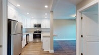 Located at 22281 Center St in Castro Valley, CA, this single-story home offers a thoughtfully updated interior with a clean, modern aesthetic. The kitchen is a standout feature, showcasing crisp white shaker cabinets, light stone-look countertops, and a full suite of stainless steel appliances including a refrigerator, electric range, over-the-range microwave, and dishwasher. A peninsula with a breakfast bar connects the kitchen to the adjacent living area, which is finished with warm wood-look flooring and a ceiling fan. The open sightlines between the kitchen and living space create a cohesive, functional layout. The bedrooms are carpeted for comfort, each equipped with ceiling fans and generous closet space, with natural light coming in through well-placed windows. Two full bathrooms feature tub-shower combinations, vanities with stone-look countertops, and brushed nickel fixtures. A dedicated hallway area provides additional built-in shelving for storage. The in-unit laundry area houses a stacked Whirlpool washer and dryer, adding everyday convenience. Warm neutral tones, recessed lighting, and consistent finishes throughout give this home a cohesive and move-in-ready feel.