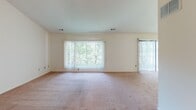 Located at 81 Fairway Ct in Lakewood, NJ, this single-floor 1-bedroom, 1-bathroom unit offers a thoughtfully laid-out living space with several notable architectural features. The living area is a standout, boasting soaring vaulted ceilings accented by a pendant light fixture, creating an open and airy atmosphere. Large windows and a sliding glass door flood the space with natural light and provide views of the surrounding greenery, while wall-to-wall carpeting adds warmth underfoot. A half-wall pass-through with a countertop connects the living area to the kitchen, maintaining an open feel between the two spaces. The kitchen is well-equipped with warm wood cabinetry extending to the ceiling for ample storage, a gas range, a refrigerator, and light-toned countertops, all set on easy-care tile flooring. The bedroom continues the carpeted flooring and features vaulted ceilings, a large closet, and a window with outdoor views, offering a comfortable and private retreat. The bathroom includes a wood-toned vanity with a generous countertop, a wide mirror with overhead lighting, white tiled walls, and a distinctive patterned tile floor, combining functionality with classic styling throughout.