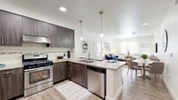 Located at 12611 Artesia Boulevard in Cerritos, CA, this well-appointed single-floor residence offers three bedrooms and three bathrooms within a thoughtfully designed open layout. The kitchen serves as a central highlight, featuring dark espresso cabinetry, granite countertops, a subway tile backsplash, stainless steel appliances including a gas range and dishwasher, and elegant pendant lighting above the island. The island doubles as a breakfast bar with seating, flowing seamlessly into the open living and dining area. The living room is bright and welcoming, with large windows that invite natural light and provide access to an outdoor area. Wood-style plank flooring runs consistently throughout, lending warmth and cohesion to the entire space. The bedrooms are comfortably sized, with the primary suite offering dedicated closet space. Each bathroom is finished with granite-topped dark wood vanities, large mirrors, and wood-style flooring, with at least one bath featuring a soaking tub with white subway tile surround. A clean, well-lit hallway connects the bedrooms and bathrooms, completing this modern and functional floor plan in the heart of Cerritos.