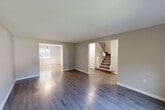 This two-story home in Lynn, MA offers a practical and well-organized layout across two evenly distributed floors. The main level features a welcoming living room with gleaming dark hardwood-style flooring that flows into a separate dining area and a functional kitchen outfitted with warm honey-toned wood cabinetry, granite-style countertops, and white appliances including a gas range and refrigerator. A central hallway connects the main living spaces and provides easy access to the carpeted staircase leading to the upper level. Upstairs, three bedrooms provide comfortable accommodations, including a generously sized primary bedroom with soft carpeting and dual louvered bi-fold closets offering exceptional storage. Additional bedrooms feature hardwood-style flooring and natural light from well-positioned windows with outdoor views. The full bathroom is cleanly appointed with white tile, a tub-shower combo, marble-look tile flooring, and a granite-topped vanity. Throughout the home, neutral warm-gray walls create a cohesive, move-in-ready aesthetic. With six closets total distributed across both floors, storage is a standout feature of this thoughtfully laid-out Lynn residence.