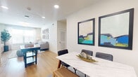 Located at 19201–19209 Kuykendahl Rd in Houston, TX, this single-floor fitness center is designed to provide a comprehensive and comfortable workout environment. The space is defined by impressively high ceilings accented with exposed decorative beams, creating an open and airy atmosphere throughout. Multiple ceiling fans and recessed lighting ensure consistent airflow and illumination across the floor.

Natural light pours in through a series of tall windows and clerestory windows positioned along the upper walls, brightening the interior and offering views of the surrounding greenery. Large wall-to-wall mirrors are strategically placed to enhance the sense of space and support proper exercise form.

The facility is well-equipped with a wide variety of cardio machines, including treadmills and ellipticals, as well as a broad selection of strength-training equipment such as cable machines, multi-station weight machines, and benches. A dedicated free weights area features a full rack of dumbbells in graduated sizes, complemented by kettlebells and fitness accessories including yoga and foam rollers.

The flooring consists of multi-toned carpet tiles in teal, blue, and neutral tones, adding both comfort underfoot and visual character. Wall-mounted televisions are positioned for easy viewing during workouts. The overall design balances functionality with an inviting, modern aesthetic suited for a wide range of fitness activities.