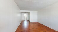 Located at 700 Euclid Ave in Miami Beach, Florida, this single-floor unit offers a straightforward and functional layout with a distinct vintage character throughout. Rich, warm-toned hardwood floors extend across the main living areas and bedrooms, adding a timeless quality to the space. The open layout of the living area flows naturally toward the rear of the unit, where a ceiling fan provides comfortable airflow, and a windowed door allows natural light to filter in from outside.

The kitchen is efficiently arranged with wooden cabinetry, white laminate countertops, a gas range, and a full-size refrigerator. Tile flooring in the kitchen provides a practical transition from the hardwood in the adjoining rooms. The space is compact but well-organized, offering all essential cooking amenities.

The bathroom is a notable feature, showcasing a retro mid-century aesthetic with terracotta-toned wall tiles accented by teal trim, a matching teal bathtub and toilet, and white floor tiles. A louvered window above the tub brings in natural ventilation and light.

The bedrooms are simply finished with white walls and the same rich hardwood floors found throughout, offering clean, neutral spaces. Structural ceiling beams add a subtle architectural detail to the interior. The unit's location in Miami Beach places it within close proximity to local amenities, dining, and the iconic South Beach waterfront.