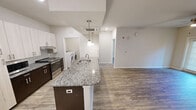 This contemporary 900 square foot apartment offers a thoughtfully designed living space with two bedrooms and two full bathrooms. The open-concept layout seamlessly integrates the kitchen, living, and dining areas, creating a spacious feel. The kitchen is a highlight, featuring sleek granite countertops, stainless steel appliances, and a combination of light and dark cabinetry for a modern aesthetic. In-unit laundry adds convenience, while the bathrooms boast granite vanities and large mirrors. Throughout the apartment, wood-look flooring adds warmth and durability. The bedrooms are well-proportioned, with the primary bedroom measuring 160 square feet. Large windows in each room allow for ample natural light, and ceiling fans provide additional comfort. Climate control is ensured with both central air conditioning and a mini-split system. The neutral color palette throughout offers a blank canvas for personalization, making this apartment an ideal space for modern, comfortable living.