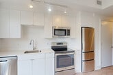 Located in the vibrant Dupont Circle neighborhood of Washington, DC, this efficiently designed studio offers a clean, contemporary aesthetic throughout. Light-toned hardwood flooring flows seamlessly across the main living area, complemented by crisp white walls that enhance the sense of openness. A large, multi-pane picture window floods the living space with natural light while framing views of the charming surrounding brick rowhouses and lush tree canopy.

The modern kitchen is thoughtfully appointed with sleek, flat-front white cabinetry extending to the ceiling for maximum storage. A full suite of stainless steel appliances—including a refrigerator, electric range, over-the-range microwave, and dishwasher—provides everything needed for daily cooking. Light countertops and a single-basin sink complete the functional workspace, all illuminated by track lighting overhead.

The bathroom features large-format, light-toned tile flooring and a full tub-shower combination with marble-style tile surround, conveying a clean and polished finish. A dedicated entrance area provides a practical transition into the living space. The unit's thoughtful layout and neutral palette make it highly versatile, offering a modern urban retreat in one of Washington's most walkable and sought-after neighborhoods.