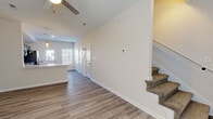 This two-story home offers a thoughtfully designed layout with clean, modern finishes and a neutral color palette that creates a bright and welcoming atmosphere throughout. The main floor features durable wood-look luxury vinyl plank flooring that flows seamlessly from the open living area through the hallway and into the kitchen. Vaulted ceilings in the living room add a sense of spaciousness, complemented by a ceiling fan and natural light from the front-facing windows. A carpeted staircase leads to the upper level. The kitchen is a standout feature, outfitted with slate-blue shaker-style cabinetry, white countertops, and a full suite of stainless steel appliances including a refrigerator with ice and water dispenser, electric range, over-the-range microwave, and dishwasher. A rear entry door and additional storage closets add everyday practicality. The bathrooms feature coordinating blue vanity cabinetry with white countertops and a tub-shower combination. Bedrooms are finished with plush carpeting and ceiling fans, offering a comfortable and restful environment. Each room is accounted for with ample closet access and well-placed windows that invite natural light. The home presents a move-in-ready interior with consistent, cohesive design choices from top to bottom.