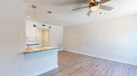 This thoughtfully designed 1-bedroom, 1-bathroom unit offers a functional and inviting layout across a single floor. The open-concept kitchen and living area serves as the heart of the space, where warm wood-look flooring, a ceiling fan with integrated lighting, and recessed lighting create a bright and comfortable atmosphere. The kitchen is equipped with white shaker-style cabinetry, granite countertops, a classic subway tile backsplash, white appliances including a range, built-in microwave, and refrigerator, as well as a deep basin sink with a modern pull-down faucet. A peninsula counter with pendant lighting connects the kitchen seamlessly to the living area, making the space ideal for everyday living. The bedroom offers plush carpeting, a ceiling fan, a natural light-filled window with blinds, and access to a dedicated closet. The bathroom features a full tub-shower combination with floor-to-ceiling white subway tile, a granite-topped vanity, and wood-look flooring. A hallway connects the main living areas to the private spaces. Neutral wall tones, clean white trim, and consistent finishes throughout lend the unit a cohesive, modern aesthetic.