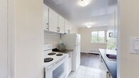 Located at 53 McMurchy Ave N in Brampton, Ontario, this well-appointed one-bedroom, one-bathroom unit offers a practical and comfortable layout across a single floor. The living room is a bright, open space highlighted by large sliding glass doors that lead to a balcony, framing lush treetop and cityscape views. Grey laminate flooring flows throughout the main living areas, complemented by warm beige walls and baseboard heating units. The spacious living area is bathed in natural light from multiple windows, creating an airy and inviting atmosphere. The galley-style kitchen is efficiently designed with white cabinetry, dark countertops, a subway tile backsplash, white tile flooring, and full-size appliances including a refrigerator and stove. The bedroom is a well-sized, private retreat featuring the same laminate flooring, a sliding-door closet for ample storage, and a window with scenic views of the surrounding neighbourhood and skyline. The full bathroom is clean and functional, finished with white tile throughout, a shower-tub combination, and a window that brings in natural light. The building exterior showcases a classic brick facade set within a landscaped green environment, adding to the overall appeal of this practical Brampton residence.