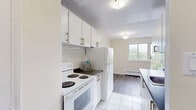 Located at 53 McMurchy Ave N in Brampton, Ontario, this well-appointed one-bedroom, one-bathroom unit offers a practical and comfortable layout across a single floor. The living room is a bright, open space highlighted by large sliding glass doors that lead to a balcony, framing lush treetop and cityscape views. Grey laminate flooring flows throughout the main living areas, complemented by warm beige walls and baseboard heating units. The spacious living area is bathed in natural light from multiple windows, creating an airy and inviting atmosphere. The galley-style kitchen is efficiently designed with white cabinetry, dark countertops, a subway tile backsplash, white tile flooring, and full-size appliances including a refrigerator and stove. The bedroom is a well-sized, private retreat featuring the same laminate flooring, a sliding-door closet for ample storage, and a window with scenic views of the surrounding neighbourhood and skyline. The full bathroom is clean and functional, finished with white tile throughout, a shower-tub combination, and a window that brings in natural light. The building exterior showcases a classic brick facade set within a landscaped green environment, adding to the overall appeal of this practical Brampton residence.