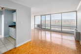 Located at 20 N Shore Blvd W in Burlington, Ontario, this two-bedroom, one-bathroom unit is thoughtfully laid out across a single floor, offering a comfortable and functional living environment. Parquet hardwood flooring is a consistent design element throughout the living areas and bedrooms, lending warmth and classic character to the space.

The living room is generously proportioned and benefits from floor-to-ceiling sliding glass doors that open onto a balcony, providing expansive outdoor views of the surrounding landscape. Crown moulding adds a refined architectural detail to this area. A second bedroom also features large floor-to-ceiling windows that frame sweeping panoramic views, filling the room with abundant natural light. Both bedrooms include ceiling fans and closet storage, with the primary bedroom featuring a dedicated walk-in closet with built-in shelving and hanging rods.

The galley-style kitchen is efficiently designed with white cabinetry, granite countertops, a stainless steel sink, and light tile flooring. The bathroom is finished with tile flooring and features a glass-enclosed walk-in shower with modern fixtures. Hallways connect the rooms cohesively, contributing to the unit's organized and practical flow.