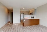 Located at 11025 26 Avenue NW in Edmonton, Alberta, this well-designed 2-bedroom, 2-bathroom unit offers a thoughtful layout with modern finishes throughout. Light wood-look flooring flows seamlessly across all rooms, creating a clean and cohesive aesthetic.

The open-concept living and kitchen area is a standout feature, anchored by dramatic floor-to-ceiling windows that flood the space with natural light and offer sweeping views of the surrounding Edmonton skyline and neighbourhood. The kitchen features a contemporary island with warm wood-toned cabinetry, stainless steel appliances, and a built-in microwave. A wall-mounted split air conditioning unit ensures year-round comfort.

Both bedrooms are well-proportioned, with the primary bedroom featuring large corner windows that maximize natural light. A sliding door closet with a built-in hanging rail provides practical storage. The second bedroom is equally versatile, with access to the hallway.

The two bathrooms are finished to a high standard, featuring marble-effect wall tiling, a walk-in glass shower in one, and a soaker tub with matching tile surround in the other. Each bathroom includes a warm-toned wood vanity with an integrated sink and a large mirror. Hallways connect the rooms efficiently, completing a functional and stylish floor plan.