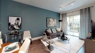 This well-appointed single-floor residence showcases a cohesive modern design characterized by bold teal accent walls, rich dark wood finishes, and granite surfaces throughout. The open-concept kitchen is a standout, outfitted with floor-to-ceiling dark espresso cabinetry, granite countertops, a classic subway tile backsplash with under-cabinet lighting, and a full suite of stainless steel appliances including a side-by-side refrigerator with water dispenser, dishwasher, microwave, and range. A center island provides additional prep and dining space, while wood-look flooring ties the kitchen seamlessly into the adjoining dining area. The living room is an inviting, light-filled space anchored by a dramatic teal feature wall, track lighting, and sliding glass doors that open to a private outdoor balcony. The bedroom continues the teal design theme, featuring a tray ceiling with a ceiling fan, a large window with sheer drapery offering outdoor views and abundant natural light, and a decorative mirrored wall panel above the bed. The bathroom is generously proportioned, with a dual-sink vanity topped in granite, dark wood cabinetry with chrome hardware, and a soaking tub with tile surround. Together, these spaces create a refined and contemporary living environment with upscale finishes throughout.