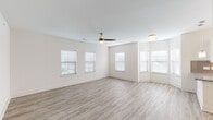 This single-floor residence offers a clean, modern aesthetic defined by a neutral color palette, abundant natural light, and thoughtfully selected finishes throughout. The spacious main living area is anchored by light-toned luxury vinyl plank flooring and features multiple windows dressed with white blinds, allowing natural light to fill the room. A ceiling fan provides additional comfort overhead.

The kitchen is a functional and attractive centerpiece, showcasing granite countertops, white shaker-style cabinetry, a subway tile backsplash, a stainless steel undermount sink, and a stainless steel refrigerator. A built-in wine rack adds a distinctive design touch, while track lighting illuminates the workspace effectively.

The bedrooms are carpeted for comfort and each include ceiling fans and windows with blinds. The primary bedroom is notably well-equipped, offering direct access to both a walk-in closet and a private en-suite bathroom featuring a glass-enclosed walk-in shower, wood-look vinyl flooring, white cabinetry, and a granite vanity countertop. A second bathroom mirrors this refined style with a soaking tub and shower combination, marble-look tile surround, and a matching granite vanity. The consistent use of quality finishes throughout creates a cohesive and polished living environment.