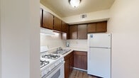 Located at 2205 Normandy Dr in Michigan City, Indiana, this single-floor unit offers a straightforward, functional layout designed for comfortable everyday living. The kitchen is equipped with dark wood cabinetry providing ample upper and lower storage, a gas range, double-basin sink, and a full-size refrigerator. Light-toned countertops contrast the rich cabinetry, and wood-look flooring adds durability underfoot. A ventilation hood above the range and overhead lighting keep the space practical and well-lit.

The living area is generously proportioned, with soft carpeting, neutral walls, and a textured ceiling. Windows allow natural light to filter in, offering views of the surrounding outdoor greenery. The open layout, visible in the floor plan scan, shows a clear flow between the kitchen and living spaces, with additional areas accessible toward the rear of the unit.

The bedroom areas feature plush gray carpeting, neutral walls, and textured ceilings. Each room benefits from natural light via windows overlooking the exterior. Closet space is well-considered, with bifold-door closets featuring full-width hanging rods and shelving. Overall, the unit presents a clean, no-frills interior well-suited for practical, comfortable living.