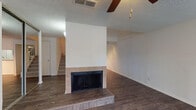 This two-story home offers a practical and comfortable layout across two levels. The main living area anchors the lower floor, highlighted by a tile-surround fireplace set against a clean white wall, with dark wood-look flooring extending throughout. A staircase leads to the upper level, and ceiling fans are present in multiple rooms for added comfort. The living space also features a sliding glass door fitted with vertical blinds, opening to an outdoor area and allowing natural light to flow in freely.

The kitchen is equipped with dark cabinetry, light quartz-style countertops, a dishwasher, and an overhead range hood, offering a functional workspace. A separate room adjacent to the kitchen provides additional flexibility.

The bathrooms are finished with wood-look flooring, a tiled walk-in shower, a floating-style vanity with stone countertops, and modern fixtures throughout. The bedrooms are carpeted and generously sized, each featuring ceiling fans and windows dressed with horizontal blinds that invite natural light. One bedroom benefits from dual windows, enhancing brightness and ventilation. Closets and connecting hallways provide ample storage and easy circulation between rooms. Textured ceilings are consistent throughout the home, adding a classic residential character to every space.