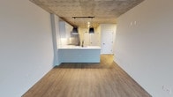 Located at 675 N Wells St in Chicago's vibrant River North neighborhood, this single-floor unit blends industrial design elements with contemporary finishes throughout. Exposed concrete ceilings serve as a defining architectural feature, lending an urban loft aesthetic that carries consistently through each room.

The open-concept kitchen is a standout, equipped with stainless steel appliances including a gas range, microwave, and French door refrigerator. Two-tone cabinetry in gray and white pairs with a white quartz countertop and a tile backsplash. A peninsula with an undermount sink and space for seating adds function, while two matte black pendant lights provide focused illumination beneath the concrete ceiling.

The living area benefits from expansive floor-to-ceiling windows framed in black, offering elevated views of the Chicago skyline and filling the space with natural light. Wood-look plank flooring runs throughout, complementing the raw ceiling texture.

The bedroom features the same exposed concrete ceiling and includes a spacious walk-in closet with built-in shelving. The bathroom is finished with white subway tile surrounding the tub and shower, a gray vanity with gold hardware, and a white quartz countertop. An in-unit washer and dryer are also included.
