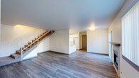 Located at 2220 Noble Ct SE in Auburn, Washington, this two-story home offers a practical and comfortable layout spread across two floors. The main level features an open-concept living room and kitchen, where durable wood-look flooring flows throughout. The living area includes a fireplace with a tiled surround, a large window with vertical blinds for natural light, and a white-railed staircase leading to the upper level. The kitchen is equipped with white cabinetry, stone-patterned countertops, a double-basin sink, and a dishwasher, offering efficient functionality. A hallway connects to additional spaces, including a patio for outdoor access and an attached garage with a sectional door, providing ample storage or parking. Two full bathrooms feature light wood-tone flooring, stone-patterned countertops, and clean white fixtures. Upstairs, two carpeted bedrooms offer a quiet retreat, each with generous closet space — four closets in total throughout the home. The primary bedroom is a comfortable size, while the secondary bedroom benefits from a large window with natural light and a baseboard heater. In-unit laundry adds everyday convenience. Neutral tones and clean finishes throughout create a move-in-ready atmosphere.