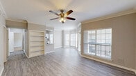 Located at 2200 Riverfront Dr in Little Rock, Arkansas, this well-appointed two-bedroom, two-bathroom residence offers a thoughtfully designed single-level layout. The open-concept living and dining area immediately impresses with light gray wood-style flooring, crown molding, a ceiling fan, and built-in shelving that adds both character and functionality. A striking bay window arrangement floods the space with natural light and opens to a private balcony, creating an inviting, airy atmosphere.

The kitchen features white cabinetry, stone-look countertops, and a full suite of stainless steel appliances, including a refrigerator, dishwasher, and range. An in-unit stacked washer and dryer is conveniently located just off the kitchen. Light tile flooring completes the clean, bright aesthetic of this space.

Both bedrooms are generously sized and finished with plush carpet and ceiling fans. The primary bedroom offers direct access to a dedicated bathroom, while each bedroom benefits from its own walk-in closet equipped with wire shelving systems for ample storage. The bathrooms are finished with stone-look countertops, white cabinetry, large mirrors, and tile flooring, with the primary bath featuring a glass-enclosed shower.