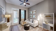 Located at 5026 Zion Rd in Garland, TX, this one-bedroom, one-bathroom residence offers a thoughtfully designed single-floor layout that maximizes every square foot. The open-concept living and kitchen area serves as the heart of the home, featuring light wood-style flooring, recessed lighting, and a ceiling fan that runs throughout the space. The kitchen is equipped with sage-gray shaker cabinetry, a white subway tile backsplash, stainless steel appliances including a refrigerator, range, microwave, and dishwasher, and a white quartz island with bar seating—ideal for both meal prep and casual dining. The living room opens directly to the outdoors through a glass door, allowing natural light to fill the space, and features neutral gray walls that complement the warm, contemporary aesthetic. The bedroom is a comfortable retreat with large windows, hardwood-style flooring, and ample natural light. The bathroom includes a glass-enclosed walk-in shower with marble-style tile surround, and connects directly to a dedicated closet with built-in shelving and hanging rods, offering practical storage. Throughout the residence, the design maintains a cohesive modern palette of warm neutrals, soft grays, and gold accents.
