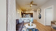 Located in San Antonio, TX, this well-appointed one-bedroom, two-bathroom residence offers a smartly designed single-floor layout that maximizes every square foot. Light wood-tone flooring flows throughout the open-concept living and kitchen area, creating a cohesive and airy atmosphere. The kitchen is a functional centerpiece, featuring dark cabinetry with a tile backsplash, stainless steel appliances, granite countertops, and a peninsula with bar seating illuminated by pendant lighting — ideal for casual dining and entertaining. The living room benefits from natural light streaming through full-height glass doors that open directly to a private balcony, extending the living space outdoors. A ceiling fan anchors the living area, enhancing comfort year-round. The bedroom is a calm retreat with a ceiling fan, a window with outdoor views, and a walk-in closet with built-in shelving. A stacked in-unit washer and dryer is conveniently located adjacent to the bedroom. Two bathrooms provide added practicality. The pantry offers additional storage, and the overall neutral color palette with soft gray walls creates a clean, modern aesthetic throughout the entire residence.