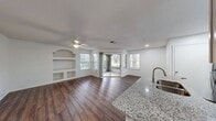 This well-designed 700 square foot apartment maximizes space and functionality. The kitchen is a standout feature, boasting sleek white cabinetry, stainless steel appliances, and granite countertops. It opens to a combined living and dining area, creating an airy, open-concept feel. 

The living space is enhanced by large sliding glass doors leading to an outdoor area, flooding the room with natural light and providing a seamless indoor-outdoor transition. Flooring varies throughout, with durable wood-look planks in main areas and plush carpeting in the bedroom.

The 140 square foot bedroom includes a ceiling fan and window, offering comfort and natural light. The bathroom features a granite vanity top and a shower/tub combination with white tile surround. 

Additional amenities include an in-unit laundry room with washer and dryer, and a closet for extra storage. The apartment's neutral color palette and modern fixtures create a contemporary, low-maintenance living environment, ideal for those seeking a compact yet well-appointed home.