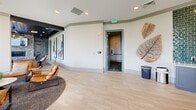 Located at Enclave Piney Lane in Asheville, NC, this thoughtfully designed community space offers a refined and welcoming atmosphere that blends contemporary aesthetics with the natural beauty of the surrounding Blue Ridge Mountains. The single-floor layout is generously proportioned, providing an open, airy feel throughout.

The space is anchored by a bright, tile-floored dining and gathering area featuring soaring ceilings with transom windows that flood the room with natural light. Expansive floor-to-ceiling windows and glass sliding doors frame panoramic mountain views, seamlessly connecting the interior to the lush, tree-covered landscape beyond. A pendant light fixture adds a warm focal point above the central dining arrangement.

A distinct lounge area features a rich dark ceiling that creates an intimate contrast with the light-toned walls. Large-scale abstract artwork adorns the walls, lending a gallery-like quality to the space. Leather seating, plush area rugs, and carefully chosen accent furnishings contribute to a sophisticated yet comfortable ambiance.

An adjacent sitting room with carpeted flooring, a dark-painted ceiling, and a built-in shelving unit opens directly onto a private balcony, offering additional mountain vistas. Decorative wall sculptures and curated art pieces are thoughtfully placed throughout, reinforcing the elevated design sensibility of this welcoming community retreat.