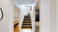 Located in the heart of downtown Duluth at 215 N First Ave E, this thoughtfully designed multi-level home offers two bedrooms and three bathrooms across three distinct floors. The main living level immediately impresses with soaring double-height ceilings and a striking steel staircase with black metal railings, creating an open, airy atmosphere flooded with natural light. Light wood flooring runs throughout, complementing the clean white walls and modern aesthetic. The combined kitchen and living room forms the social hub of the home, with ample room for both lounging and dining. A separate living room provides additional space for relaxation. The upper floors house two well-appointed bedrooms, including a generously sized primary bedroom with its own closet. Each bedroom maintains the home's clean, minimalist palette with neutral tones and hardwood floors. Three bathrooms serve the residence, including one stylishly appointed with deep dark vertical tile surrounding a soaking tub. A dedicated bathroom with stacked Bosch washer and dryer adds everyday convenience. Multiple staircases connect the levels efficiently, while walk-in wire shelving closets offer practical storage throughout. The home's vertical layout maximizes every level, making it a distinctive and functional residence in a prime urban Duluth location.