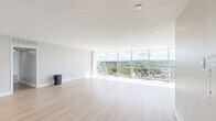 This well-appointed 2-bedroom, 2-bathroom residence at 5700 Bunkerhill Street in Pittsburgh's East End offers a modern, open layout with thoughtfully designed living spaces across a single floor. The combined dining and living area is a true highlight, featuring expansive floor-to-ceiling windows that bathe the space in natural light and frame breathtaking elevated views of the Pittsburgh cityscape and lush surrounding treetops. Light-toned hardwood flooring runs throughout the main living areas, complementing the clean, neutral color palette. The galley-style kitchen is outfitted with granite countertops, contemporary wood cabinetry, white subway tile backsplash, and stainless steel appliances, including a refrigerator, range, and built-in microwave. Both bedrooms are generously proportioned, carpeted for comfort, and benefit from large windows with the same impressive views. The spacious primary bedroom includes ample closet space. The two bathrooms echo the home's modern aesthetic with granite-topped vanities and wood cabinetry. Four closets and a dedicated laundry area provide excellent storage and convenience. A connecting hallway ties all rooms together in a cohesive, functional layout ideal for comfortable everyday living.