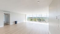This well-appointed 2-bedroom, 2-bathroom residence at 5700 Bunkerhill Street in Pittsburgh's East End offers a modern, open layout with thoughtfully designed living spaces across a single floor. The combined dining and living area is a true highlight, featuring expansive floor-to-ceiling windows that bathe the space in natural light and frame breathtaking elevated views of the Pittsburgh cityscape and lush surrounding treetops. Light-toned hardwood flooring runs throughout the main living areas, complementing the clean, neutral color palette. The galley-style kitchen is outfitted with granite countertops, contemporary wood cabinetry, white subway tile backsplash, and stainless steel appliances, including a refrigerator, range, and built-in microwave. Both bedrooms are generously proportioned, carpeted for comfort, and benefit from large windows with the same impressive views. The spacious primary bedroom includes ample closet space. The two bathrooms echo the home's modern aesthetic with granite-topped vanities and wood cabinetry. Four closets and a dedicated laundry area provide excellent storage and convenience. A connecting hallway ties all rooms together in a cohesive, functional layout ideal for comfortable everyday living.