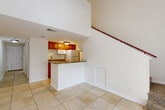 Located in Kissimmee, FL, this two-story, two-bedroom, two-bathroom residence offers a thoughtfully organized layout spread across two floors. The main level features an open-concept living area with large tile flooring and soaring ceilings that amplify the sense of space. The kitchen is equipped with warm wood cabinetry, granite-style countertops, a breakfast bar peninsula, and standard appliances, flowing seamlessly into the living area. A staircase with a wood railing leads to the upper level, which includes a loft space, adding versatile functionality to the home.

Both bedrooms are carpeted and finished with crown molding and ceiling fans, offering a comfortable and quiet retreat. Natural light filters in through windows fitted with vertical blinds. A balcony is accessible from the upper floor, providing an outdoor escape overlooking the surrounding greenery. The hallways are bright and clean, lined with closets for generous storage.

The two bathrooms are finished with tile flooring and granite-topped vanities. One features a walk-in glass-door shower, while the other includes a full soaking tub and shower combination. A dedicated utility room rounds out the practical amenities of this well-appointed Kissimmee residence.